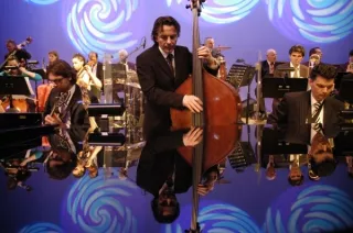 Muzikant met contrabas met op achtergrond orkest